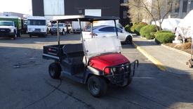 A red 2017 Toro Workman utility vehicle with a flatbed and a clear windshield parked in a lot