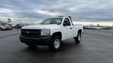 A 2013 Chevrolet Silverado 1500 pickup truck in white with a black grille and chrome wheels parked on asphalt