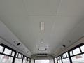 Interior view of a bus with a smooth white ceiling and multiple overhead lights