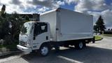 A white 2016 Isuzu NPR box truck with a large cargo area and a flatbed design parked at an angle