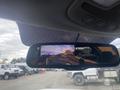 Rearview mirror displaying a backup camera view showing a roadway and vehicles behind a 2017 Ford F-550 with orange guidelines for parking assistance