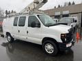 A 2008 Ford Econoline van with a cherry picker mounted on top and a white exterior parked on a wet surface