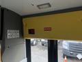 Interior view of a 2017 Chevrolet Express showing yellow padding on the ceiling with a warning sign to watch your head and an emergency release instruction on the wall