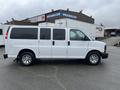 A white 2012 Chevrolet Express van with sliding side doors and chrome wheels parked with a clean exterior