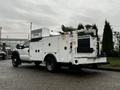 A 2015 Ford F-550 service truck with a white utility body featuring storage compartments and equipment mounted on the rear