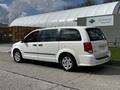 A 2011 Dodge Grand Caravan in white parked on a concrete surface showcasing its sleek design and spacious side profile