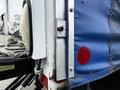 Close-up view of the rear corner of a 2006 Hino 268 featuring a blue tarpaulin a red reflector and metal components attached to the truck's body