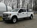 A white 2020 Ford F-350 Super Duty truck with a crew cab and chrome accents parked on a paved surface with visible tires and a front grille