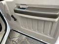 The interior door panel of a 2010 Ford F-250 SD featuring a large handle a textured surface and a crank handle for the window