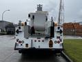 A white 2013 International DuraStar bucket truck seen from the rear with orange lights and various controls on the back panel