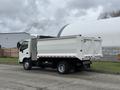 A white 2014 Hino 195 truck with a dump bed is parked on the street facing left