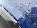 A close-up of a blue 2011 GMC Sierra 3500HD showing a scratched area on the surface with water droplets around it