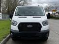 A white 2023 Ford Transit van facing forward with a distinctive black grille and headlights visible on the front