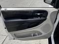 Door panel of a 2011 Dodge Grand Caravan featuring black leather and plastic accents along with power window controls and a speaker