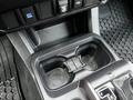 A close-up of the center console of a 2022 Toyota Tacoma featuring two cup holders and various control buttons