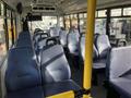 Interior of a 2018 Chevrolet Express with multiple rows of navy blue upholstered seats and yellow poles for support