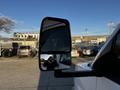 A 2017 Chevrolet Express van with a side mirror reflecting the driver holding a camera