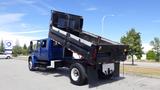 A blue 2012 International DuraStar 4300 dump truck is parked with its bed raised, showcasing the loading area at an angle designed for unloading materials