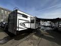 A 2021 Grand Design Recreational 311BHS travel trailer with a sleek exterior design featuring a slide-out section and an awning on the side