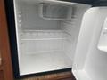 An empty interior of a refrigerator with a removable shelf and a plastic container on a ledge