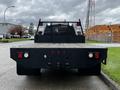 A black 2017 Ford F-550 truck with a flatbed and a metal mesh rear is parked on a street facing forward