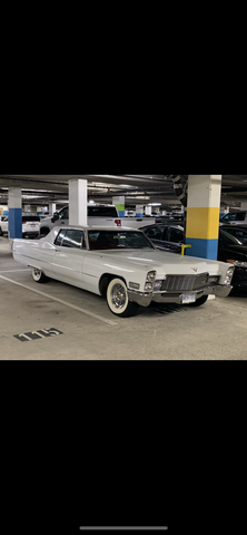 A vintage 1968 Cadillac Deville coupe in silver color with chrome accents and whitewall tires, parked in a parking garage