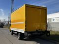 A 2017 Hino 155 box truck with a bright yellow exterior parked on the street facing away from the viewer