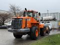 A 2018 Doosan DL300-5 wheel loader with large tires and a bucket attached in the front orange and gray color scheme