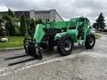 A green 2014 JLG 10054 telehandler with large tires and a front fork attachment positioned on a paved surface
