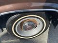 A close-up of the wheel of a 1982 Mercury Grand Marquis featuring a chrome hubcap with a red accent and a whitewall tire