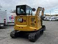 A yellow 2024 Caterpillar 306 excavator with a cab and tracks is parked with its shovel arm extended and the back facing the viewer