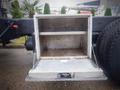 A metallic storage compartment with an open door mounted on the back of a 2013 International 5900i truck displaying an empty interior with shelves inside