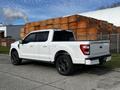 White 2021 Ford F-150 with black wheels parked at an industrial location