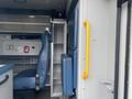 A 2014 Chevrolet Express interior featuring a blue driver seat a gray storage cabinet and a yellow grab handle