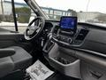 Interior view of a 2021 Ford Transit featuring a dashboard with a touchscreen display and various controls in a spacious cabin setting