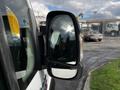 A side mirror of a 2019 RAM Promaster reflecting the sky and a parked car in the background