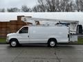 A 2009 Ford Econoline van in white with a raised aerial lift attachment on the roof and a side door open
