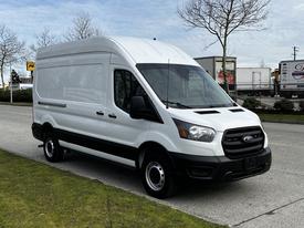 A 2020 Ford Transit van with a white exterior and a black stripe along the bottom parked on a street