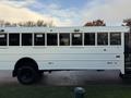 A white 2015 International 3000 school bus with multiple windows and a large entrance door on the side