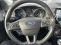 Steering wheel of a 2019 Ford Escape featuring the Ford logo with controls for audio and cruise settings