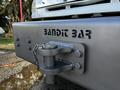 A heavy-duty bumper with the text BANDIT BAR prominently displayed and a hitch attachment secured with a chain