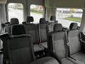 Interior view of a 2021 Ford Transit showing multiple rows of black upholstered seating with headrests and seat belts