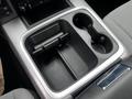 A view of the center console in a 2022 RAM 1500 Classic featuring cup holders and a compartment with a sliding cover