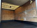 An empty interior of a 2015 Hino 195 box truck with wooden walls and a black floor