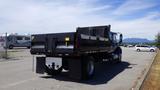 A blue 2012 International DuraStar 4300 dump truck with a black bed and dual rear wheels parked in an outdoor area