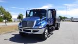 A blue 2012 International DuraStar 4300 truck featuring a flatbed and large front grille with distinctive chrome details and multiple headlights