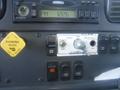 Dashboard controls of a 2005 Freightliner M2 106 Medium Duty featuring buttons for engine brake tarp operation and a parking brake lever