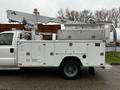 A white 2004 Ford F-450 SD utility truck with a hydraulic lift and storage compartments on the side