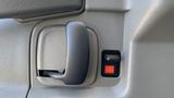 Close-up of the door handle and lock mechanism of a 2011 Chevrolet Express with a textured surface and a red indicator next to the lock