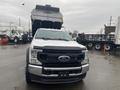 A 2021 Ford F-550 with a large open truck bed facing forward in a parking area